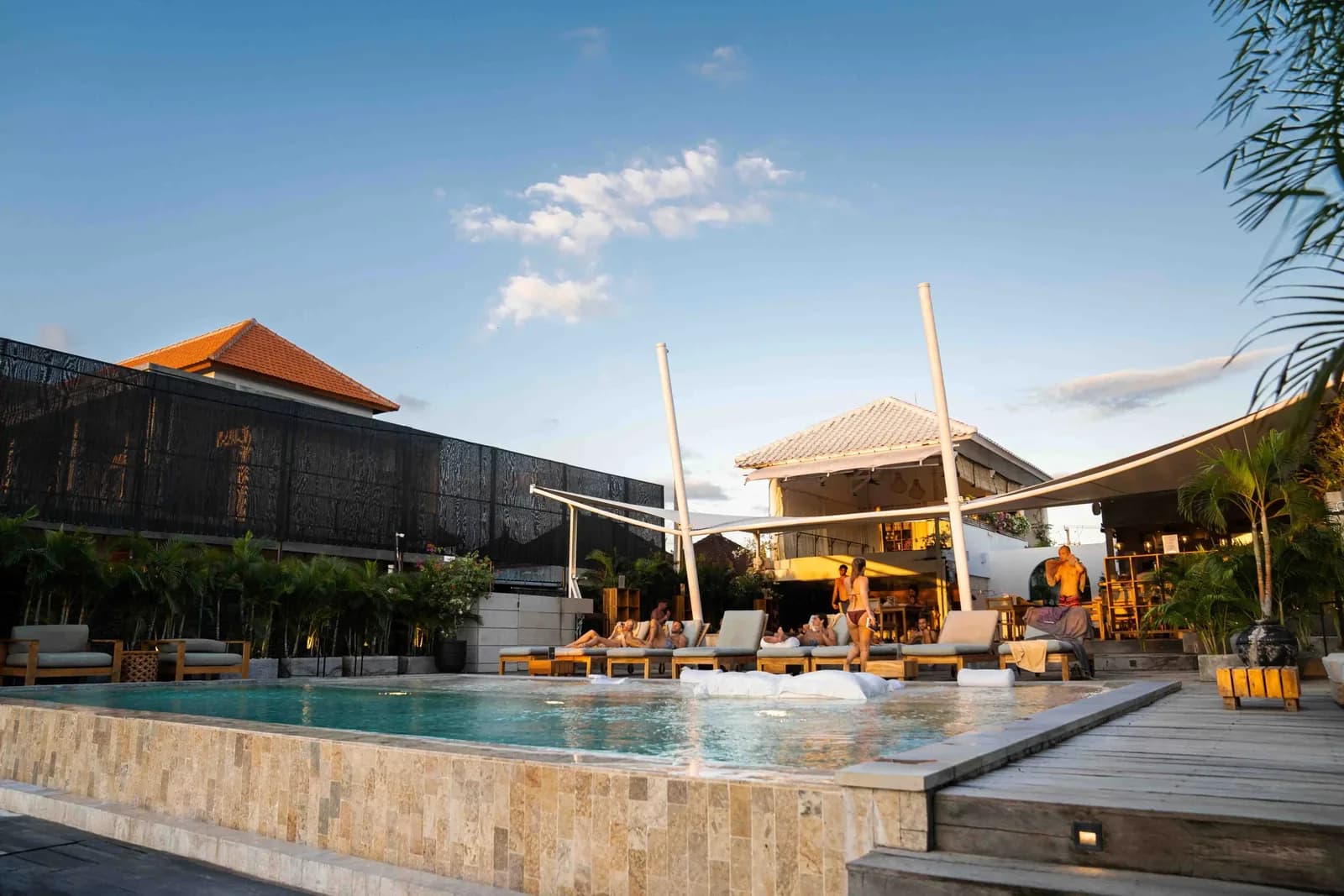 People on loungers around the pool deck at Body Factory Canggu at sunset